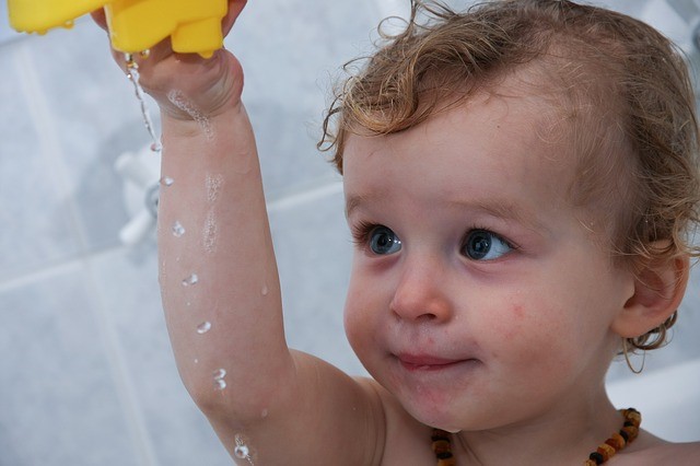 child in bath playing with toys